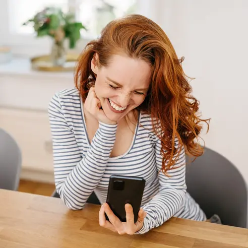 Dame mit Handy, lächelt nachdem sie den Roller Newsletter erhalten hat